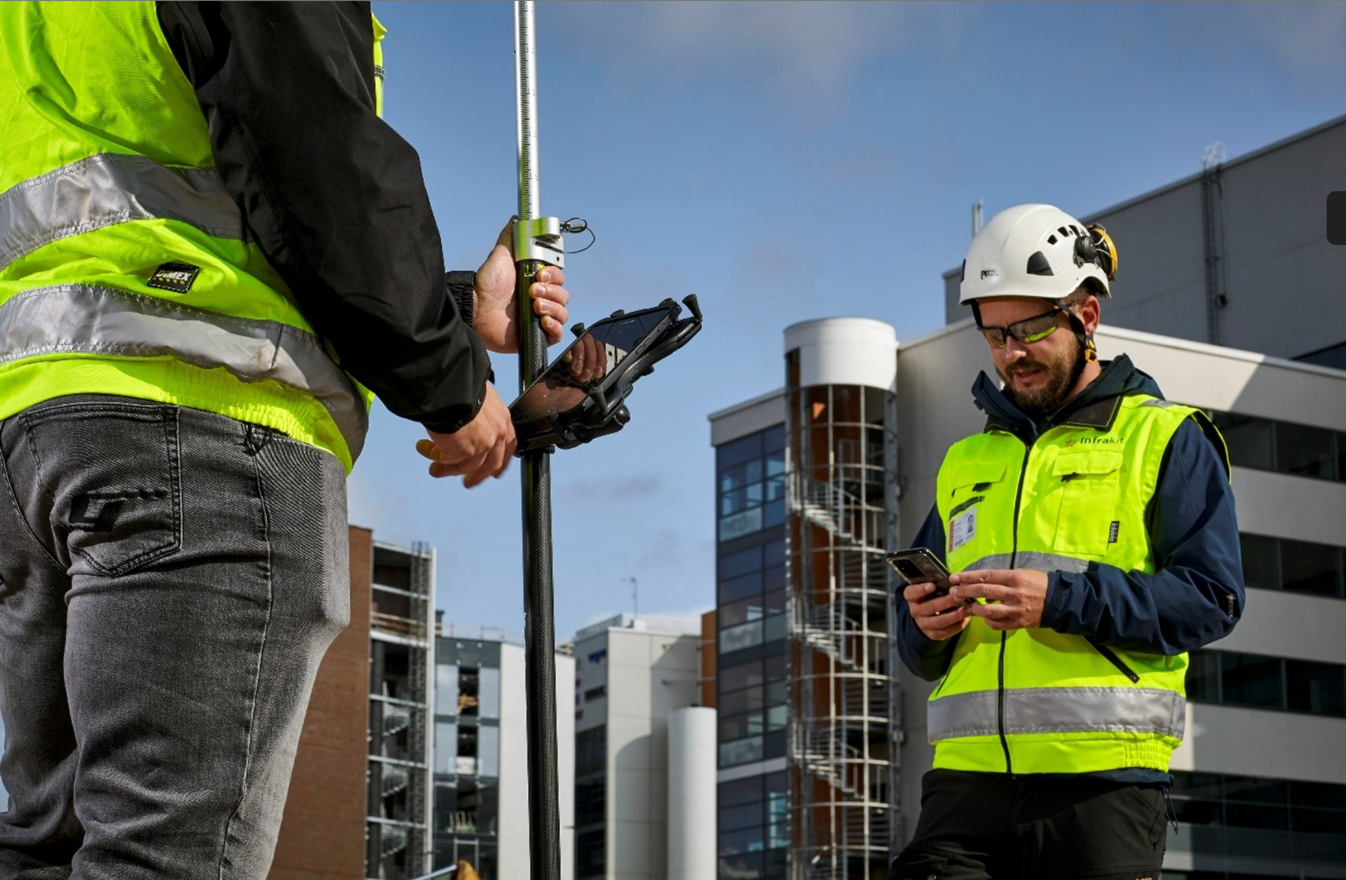 Vermesser und Bauleiter mit Tablet und Smartphone auf der Baustelle